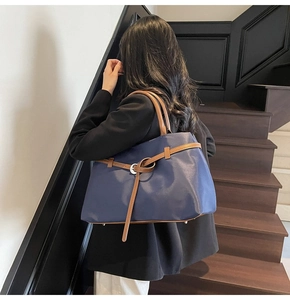 Detail of a large navy blue tote bag with brown straps in a modern business interior