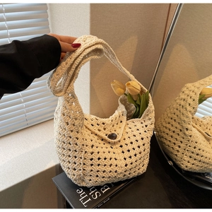 Close-up of beige crochet knit bag with geometric hollow patterns and button closure