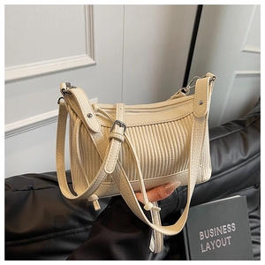 Vue détaillée de la texture du cuir plissé crème et de la boucle argentée du sac à main