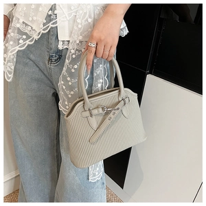Details der grauen Plissee-Handtasche mit silberner Verzierung und moderner Textur