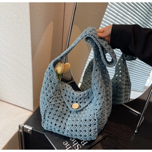 Detail of blue crochet bag with hollow knit pattern, wooden button, and floral accents
