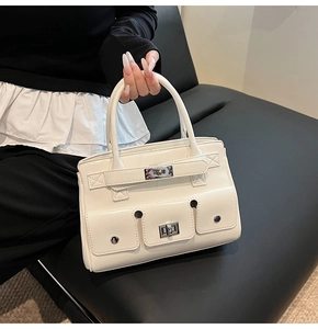 Detail shot of a white PU leather handbag featuring three front pockets and a turn-lock