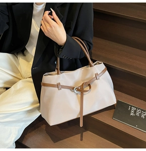 Detail of high-capacity tote bag with beige nylon fabric and dark brown leather accents