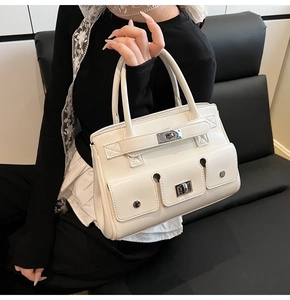 Detail of white glossy leather handbag with buckle closure and utility pockets