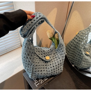 Close-up of a blue hollow knit bag featuring a round wooden button and woven texture