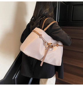 Detail of nylon tote bag with brown leather handles and decorative buckle straps