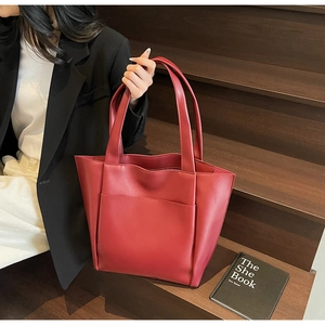 Detail of burgundy large leather tote bag with front pocket on a wooden staircase