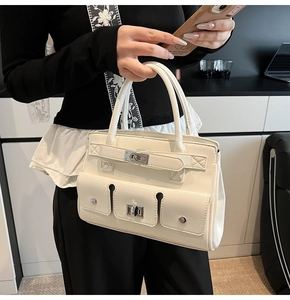 Detail of white leather handbag featuring functional pockets and silver turn-lock closure
