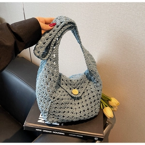Detail of light blue crochet bag with hollow weave pattern and wooden button closure