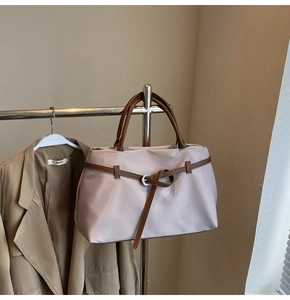 Detail of lavender nylon tote bag with brown leather straps and metal buckle accents
