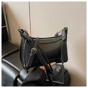 Détail d'un sac noir en cuir grainé avec design plissé vertical et bandoulière réglable argentée