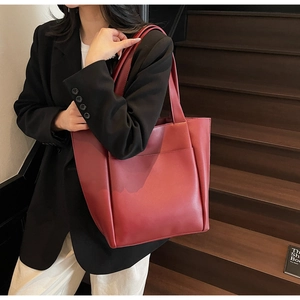 Close-up of minimalist red matte leather tote bag featuring a practical front pocket detail