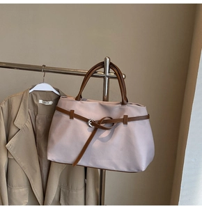 Detail of light pink nylon tote bag with brown leather straps and metal ring buckle