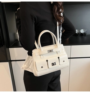 Detail of white multi-pocket handbag with silver turn-lock closures and smooth faux leather