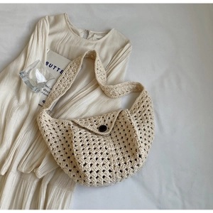 Detail of hollow knit texture and brown button on a beige crochet half-moon bag