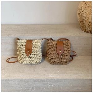 Detail of mini woven straw crossbody bags with leather snap closure in beige and tan