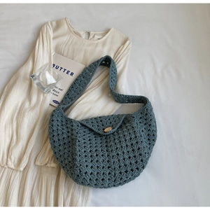 Close-up of hollow crochet weave texture with wooden button on a blue knit bag