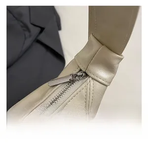 Detail of silver zipper and reinforced shoulder strap stitching on beige faux leather bag