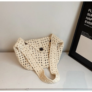 Detail der handgehäkelten cremefarbenen Strandtasche mit Lochmuster und Knopfverschluss