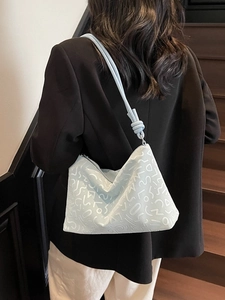 Sac fourre-tout bleu clair à motifs géométriques porté par un mannequin en costume