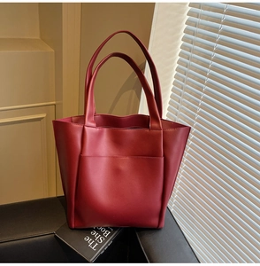 Detailed shot of dark red tote bag featuring a front pocket and matte leather texture