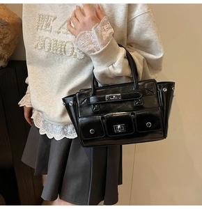 Detail of black glossy leather handbag featuring silver hardware buckles and outer pockets