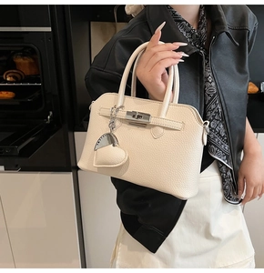 Dettaglio borsa beige in pelle martellata con chiusura argento e ciondolo a cuore