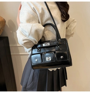 Detailed side view of black patent leather crossbody bag with multiple silver buckle pockets