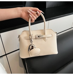 Dettaglio borsa in pelle martellata bianco crema con chiusura argento e ciondolo cuore