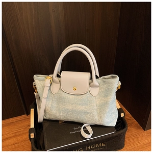 Dettaglio della borsa tote in denim azzurro con manici in pelle grigia e finiture dorate