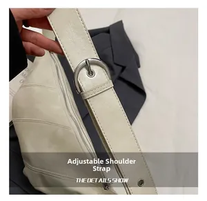 Detail showing adjustable faux leather shoulder strap with silver buckle on cream bag