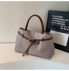 Detail of lavender tote bag with decorative brown leather strap and silver metal buckle