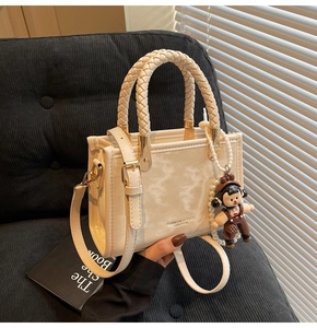 Detail view of cream crossbody bag with woven handle and cute cartoon charm