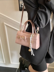 Schicke rosa Umhängetasche mit Schleife und Seidenschal an Model im schwarzen Anzug