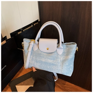 Dettaglio della borsa tote in denim azzurro con manici in pelle e fibbia in metallo dorato