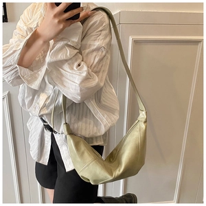 Detail of pea green dumpling bag showing soft leather texture and adjustable shoulder strap