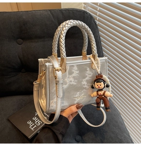 Detail of silver metallic handbag featuring marble texture and a cute girl charm accessory