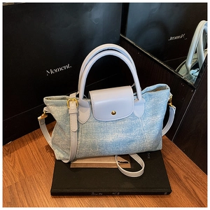 Dettaglio borsa in denim azzurro con manico in pelle lavanda e fibbia in metallo oro