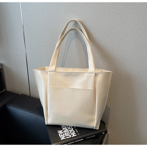 Detail shot of a minimalist cream leather tote bag featuring a large front pocket and strap