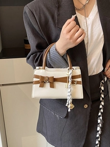 Minimalistische beige kleine quadratische Handtasche mit braunen Griffen und Schleife