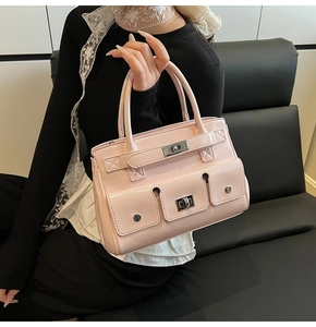 Detail of pink glossy leather handbag showing silver twist lock and functional front pockets