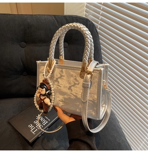 Detail of silver metallic textured crossbody bag with pearl chain and cartoon pendant