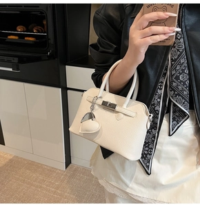Dettaglio della borsa in pelle litchi bianco crema con chiusura a scatto e ciondolo a cuore
