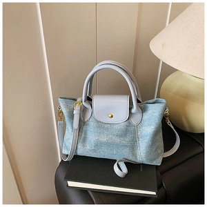 Dettaglio della borsa tote denim azzurro con manici in pelle e chiusura dorata