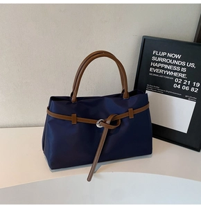 Close-up of navy nylon tote with brown leather handles and silver buckle details
