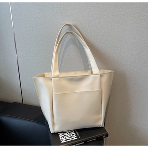Close-up of cream leather tote bag with large front pocket on decorative books