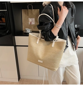 Detail of woven straw tote bag with white leather trim and twisted rope handle texture