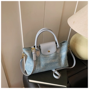 Vista dettagliata della borsa tote in denim azzurro con manici in pelle e fibbia d'oro