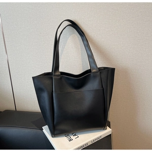 Close-up of the large capacity black tote bag showing smooth leather texture and front pocket