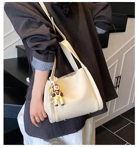 Close-up of off-white lychee leather bucket bag with fashion print and pearl charm